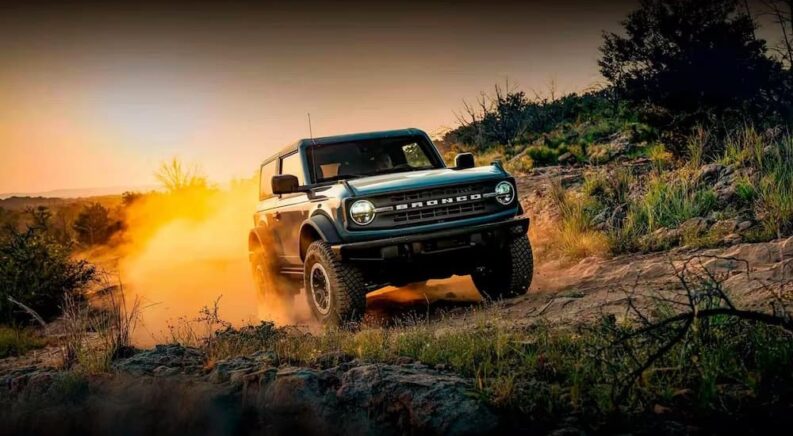 A green 2024 Ford Bronco is shown driving off-road after receiving auto repair.