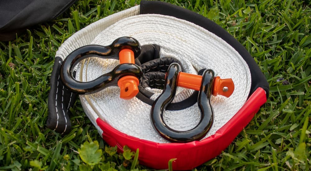 A snatch strap and two bow shackles are shown on grass.