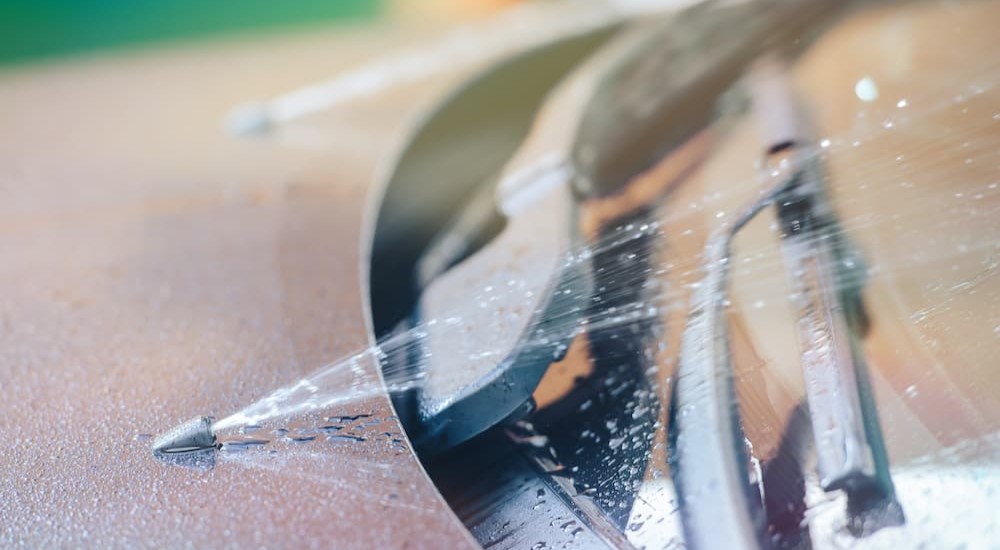 Windshield wiper fluid is shown being sprayed onto a windshield.