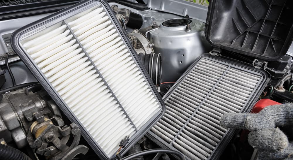 A pair of engine air filters being held by a mechanic.