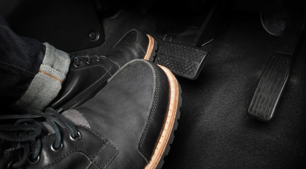 A pair of shoes are shown pressing on pedals in a vehicle.