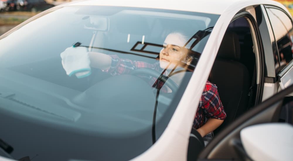 A person is shown wiping her windshield with a cloth.