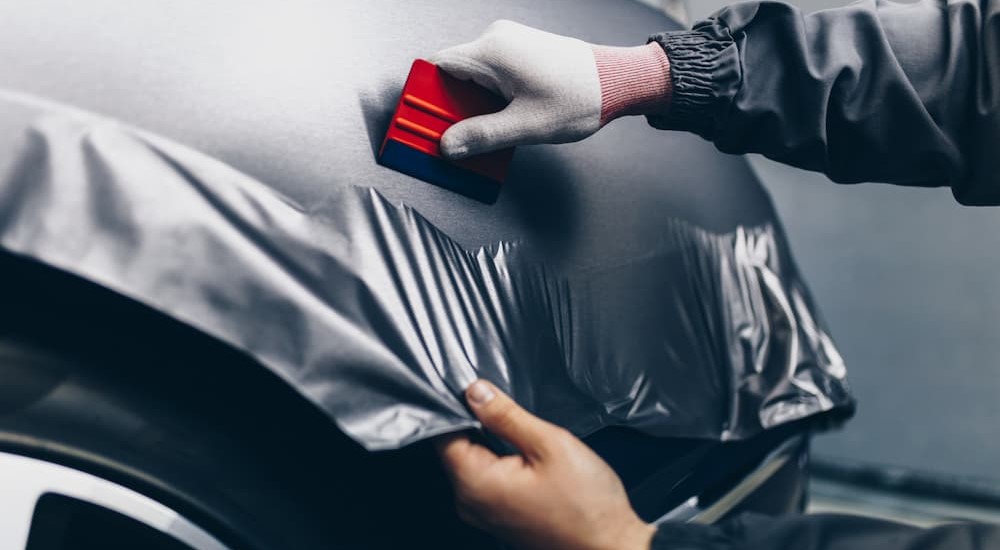 A technician is shown using a squeegee on a car wrap.