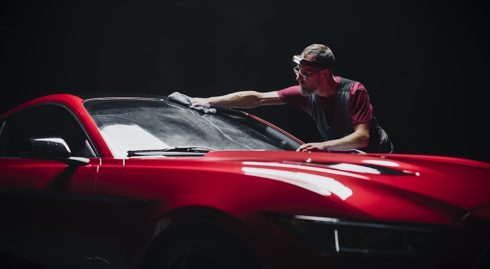 A man is shown washing the windshield of a red 2017 Ford Mustang.