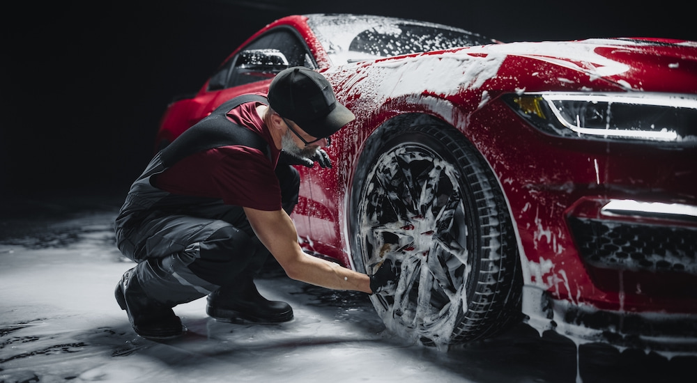 A man is shown washing the wheel of a red 2017 Ford Mustang.