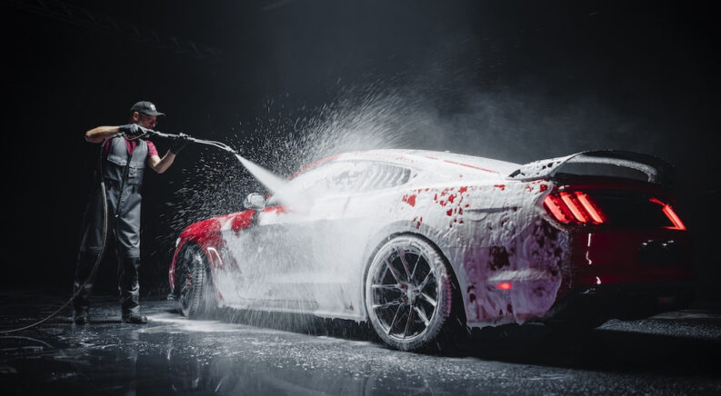 A man is shown washing a red 2017 Ford Mustang.