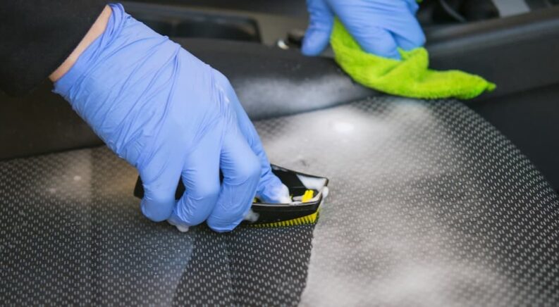 A person is shown cleaning the interior of a vehicle.