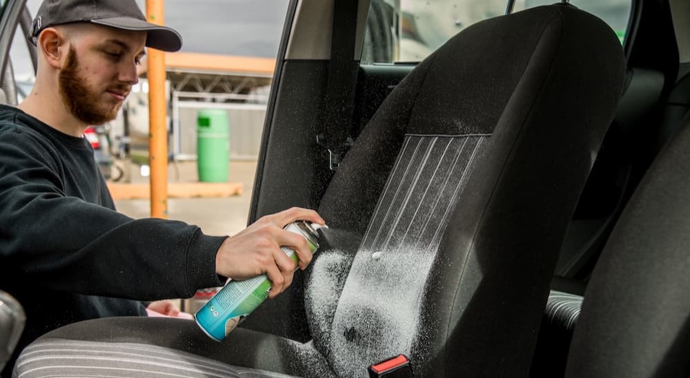 A person is shown cleaning the interior of a vehicle.