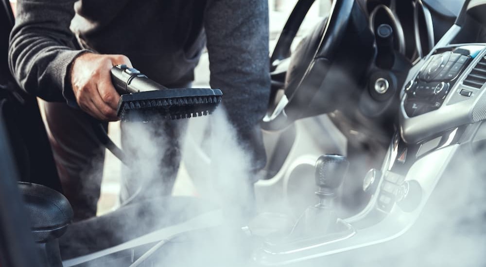 A person is seen steam cleaning the interior of a vehicle.