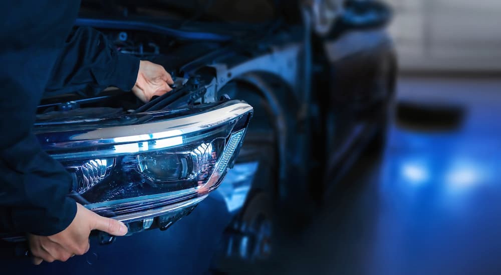 A mechanic is shown working on the headlight on a vehicle.