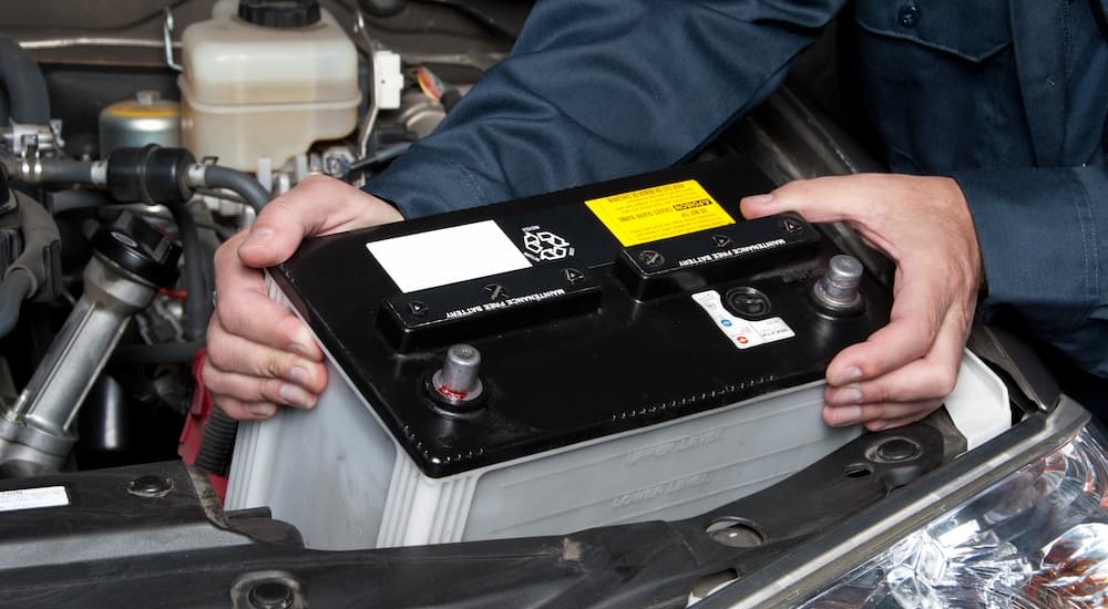 A mechanic is shown holding a battery.