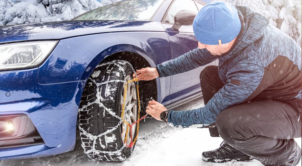 A person is shown installing tire chains on his vehicle.