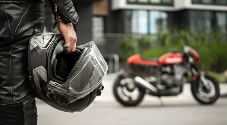 A biker is shown holding a helmet.