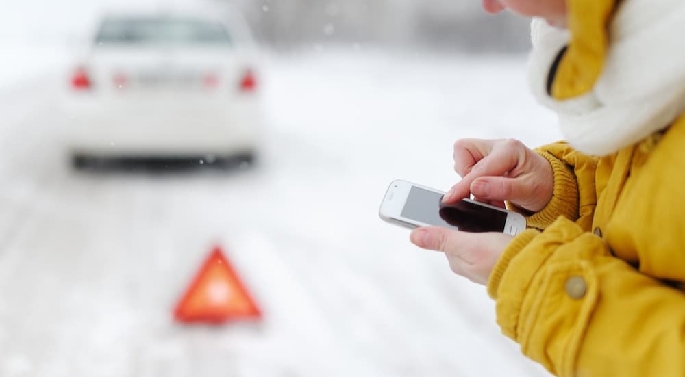 A person is shown using a cell phone near an emergency reflective triangle.