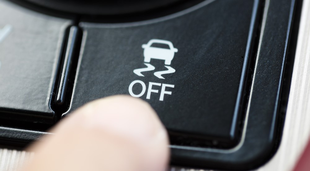 A finger is shown pressing the traction control off button.