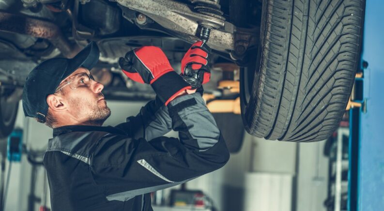 A mechanic is shown performing a strut replacement.