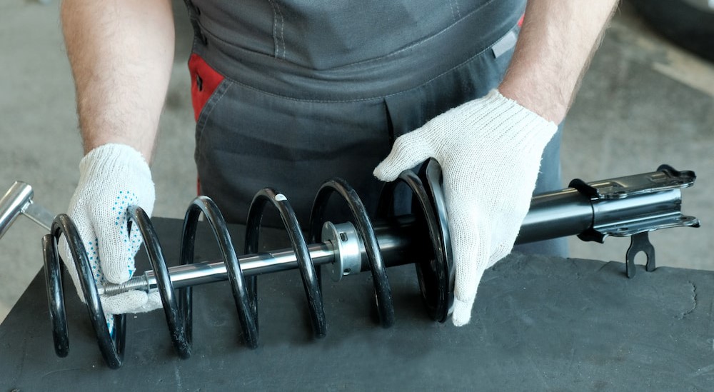 A technician is shown inspecting the shock absorber and strut.