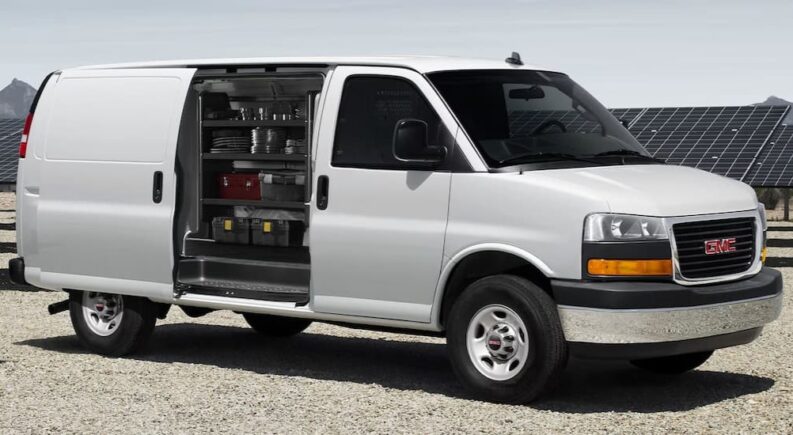 A white 2025 GMC Savana 1500 Cargo Van is shown parked after performing a delivery van service.