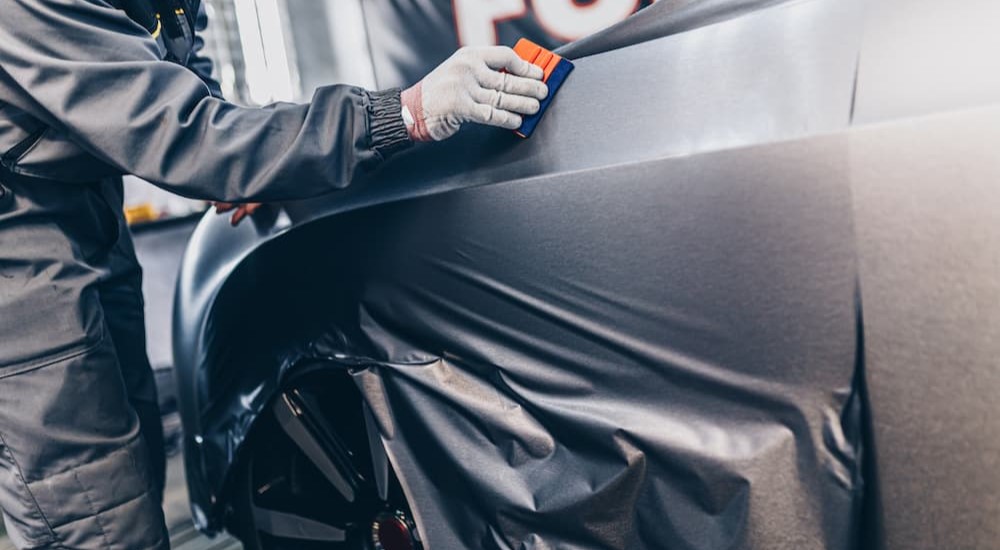 A technician is shown vinyl wrapping a vehicle.