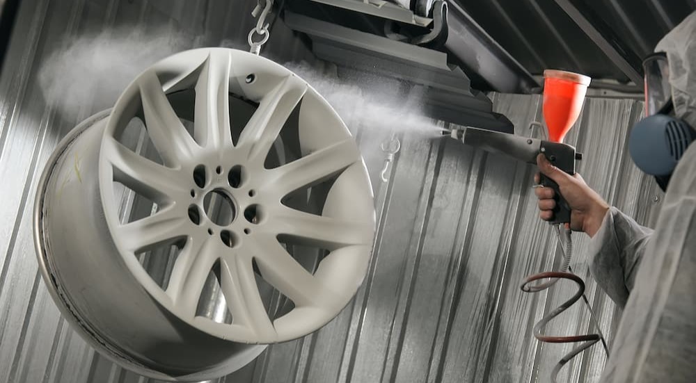 A technician is shown painting a vehicle's rim.