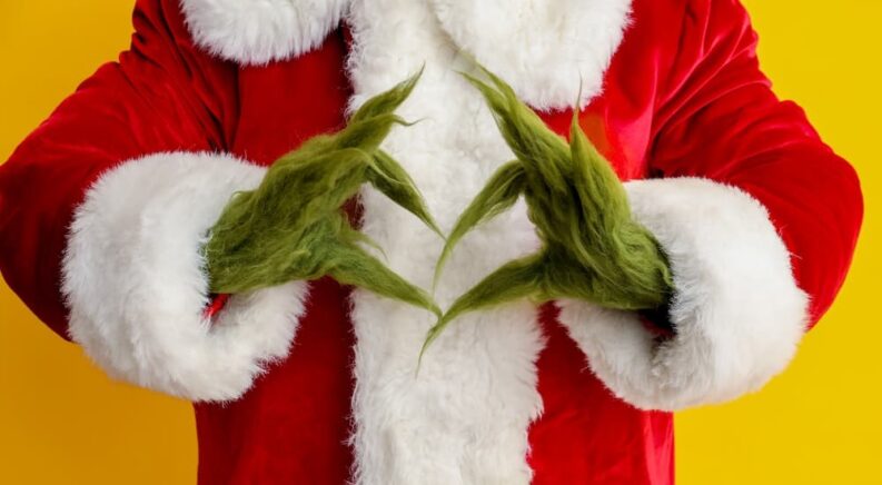 The Grinch is shown making a heart with his hands.