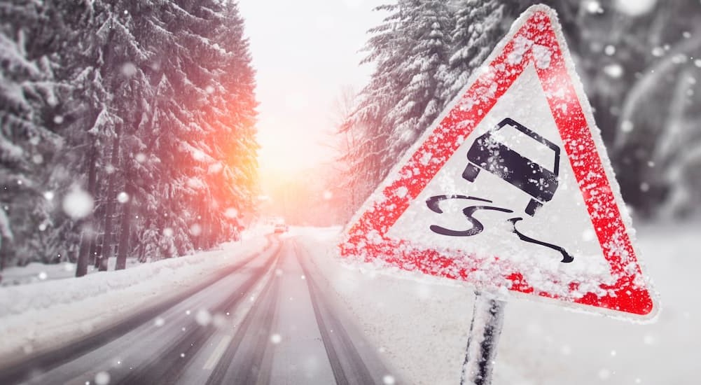 A triangular warning sign is shown on a snowy day.