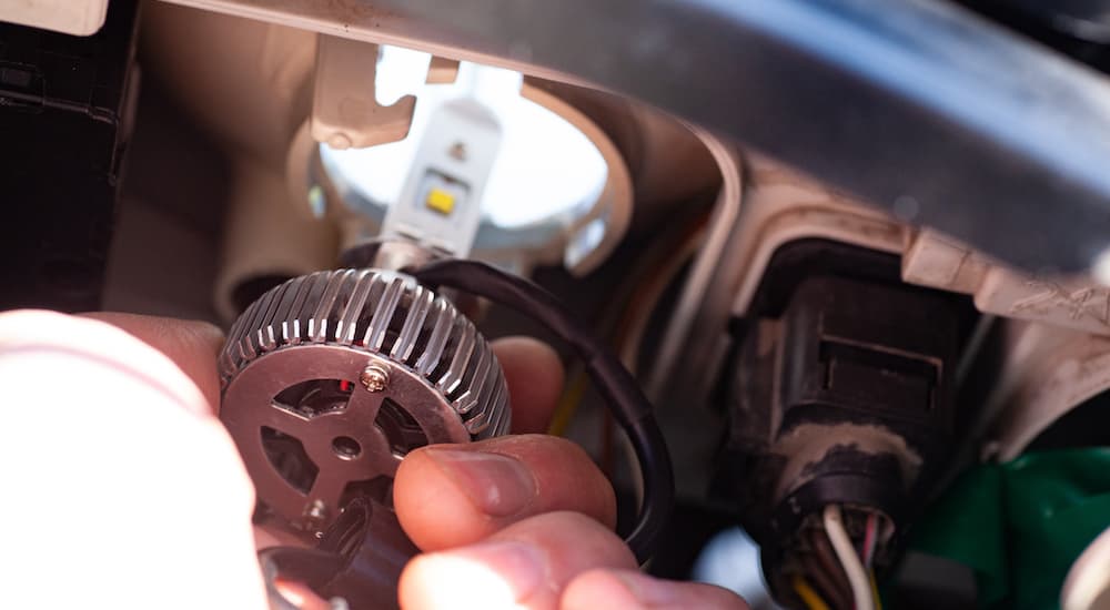 A close-up shows a person installing and LED bulb on a vehicle.