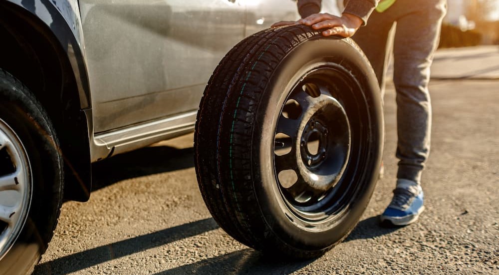 A person is shown pushing a spare tire.