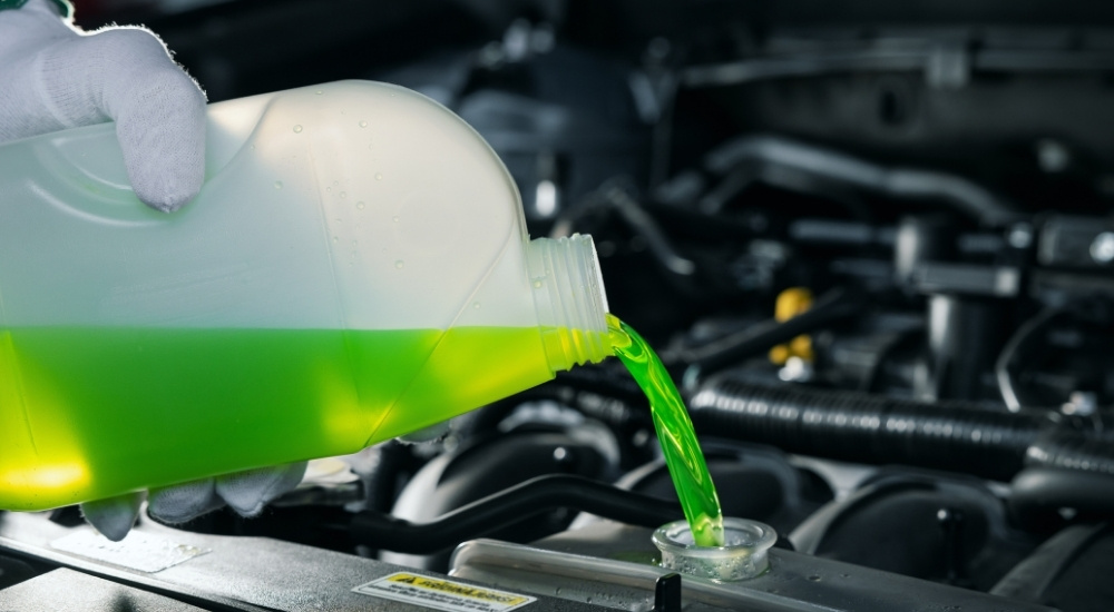 Green coolant is shown being poured into an engine.