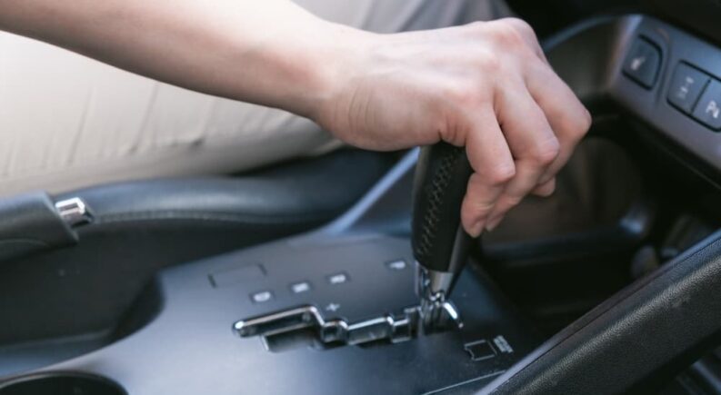 A hand is shown shifting a car into park.