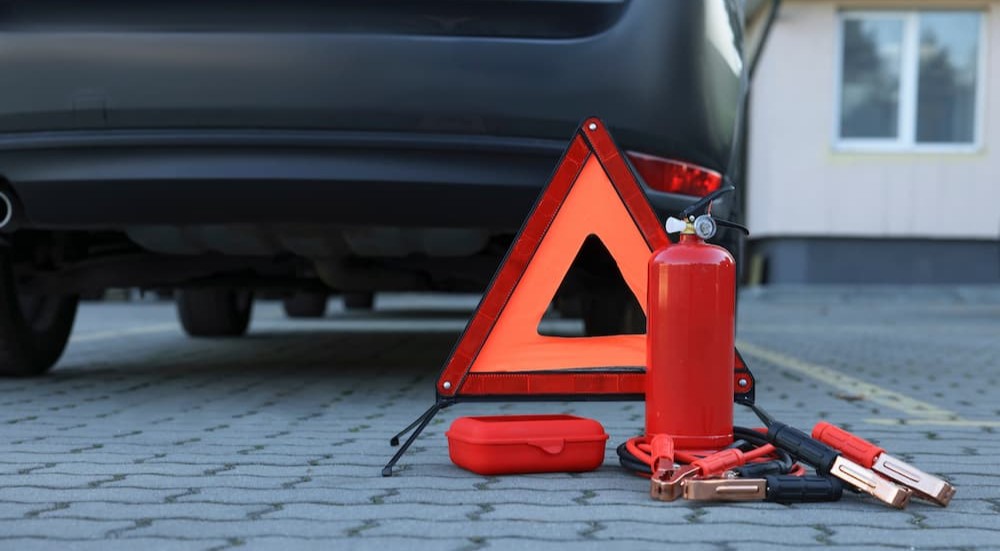 An emergency kit is shown on the ground behind a vehicle.