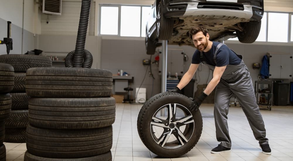 A technician is shown pushing a tire in a garage.