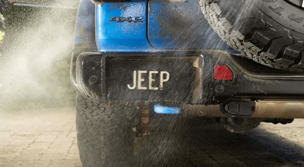 A close up of the rear bumper and plate on a blue 2025 Jeep Wrangler 4xe while being cleaned.