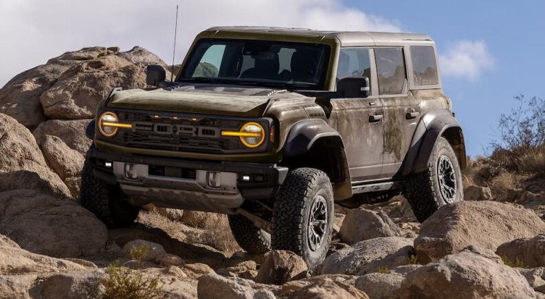 A brown 2025 Ford Bronco Raptor off-roading over a rocky trail.