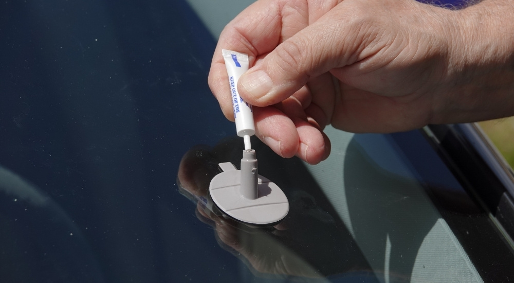 Someone is shown applying resin to a windshield crack.