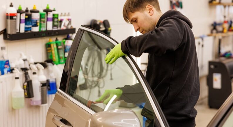 A technician is shown fixing a car window.