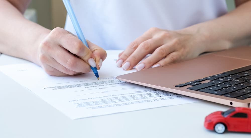 A woman signing car insurance paperwork