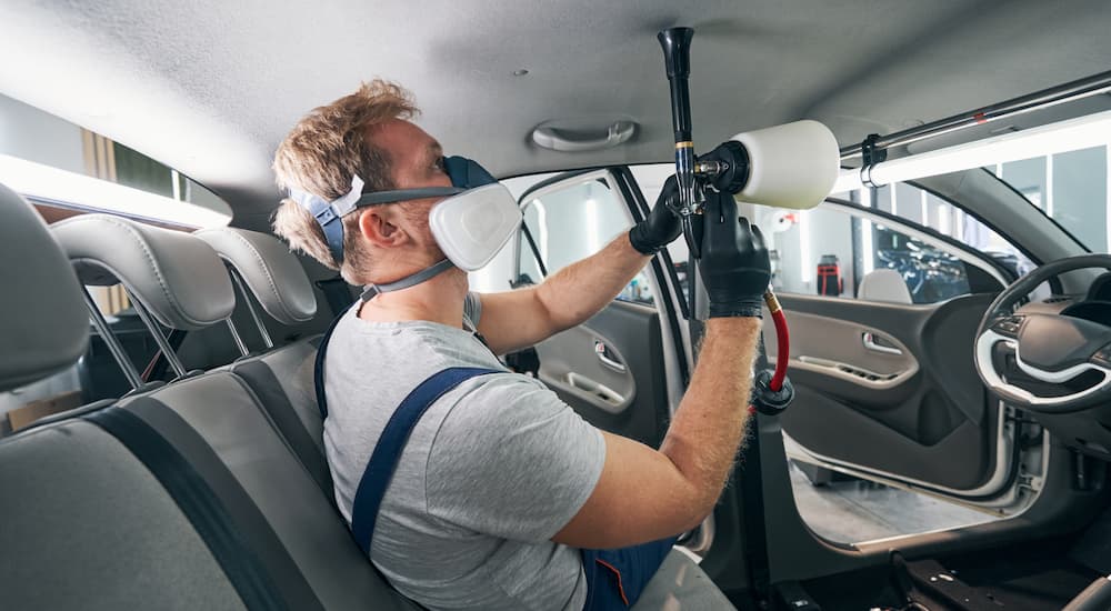 A repair man cleaning the headliner in a vehicle