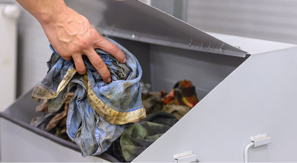 Dirty oil rags being placed into a recycling bin.