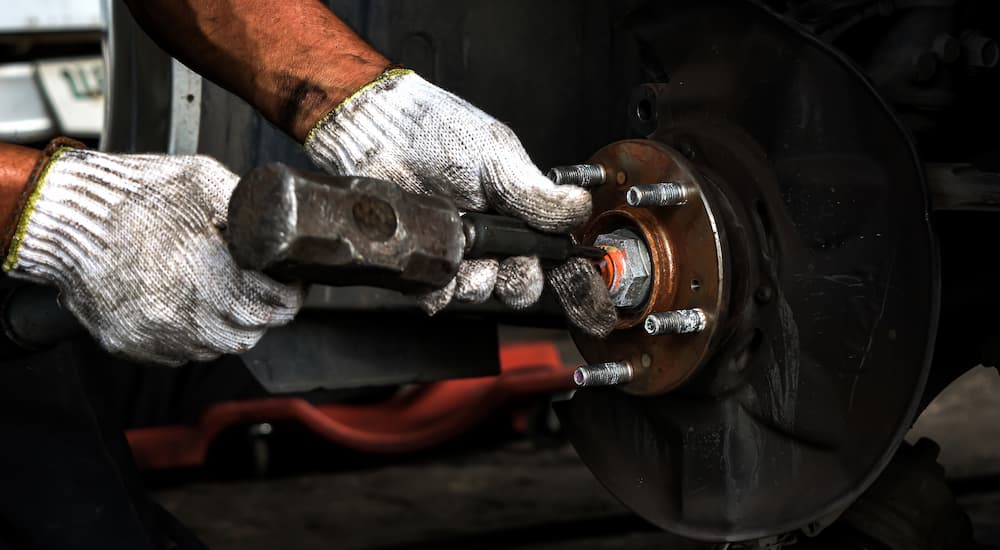 A person works on the wheel hub and wheel bearing of a car.