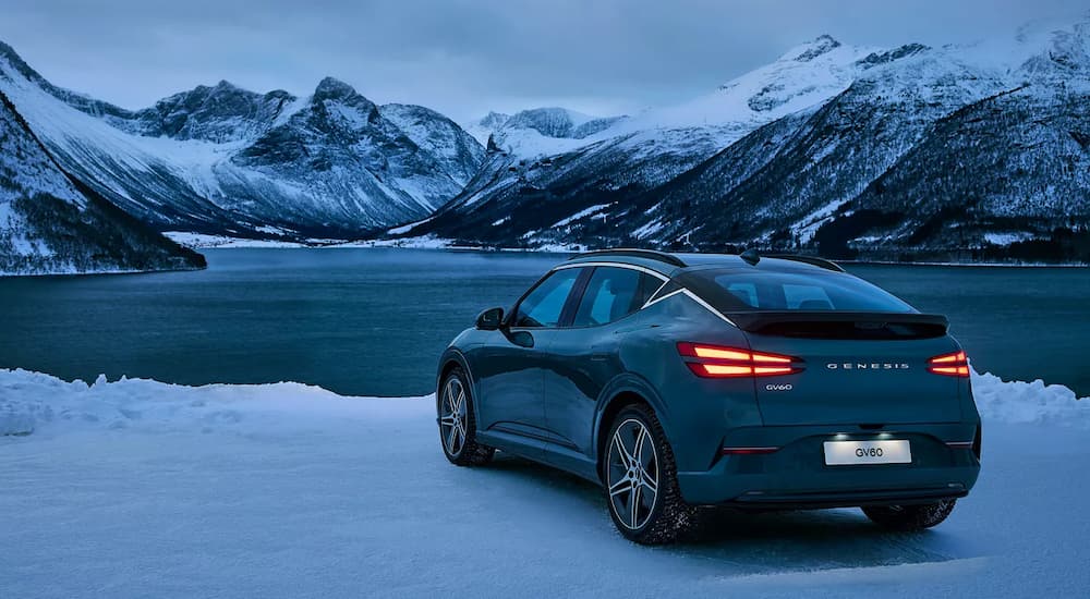 A blue 2026 Genesis GV60 parked at a lake in snow