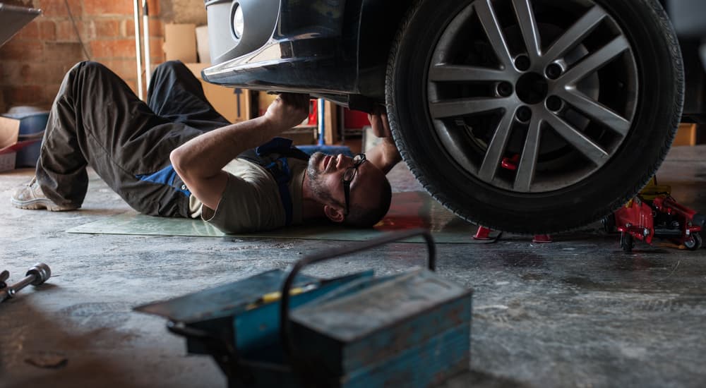 A person working under their vehicle from a home garage.