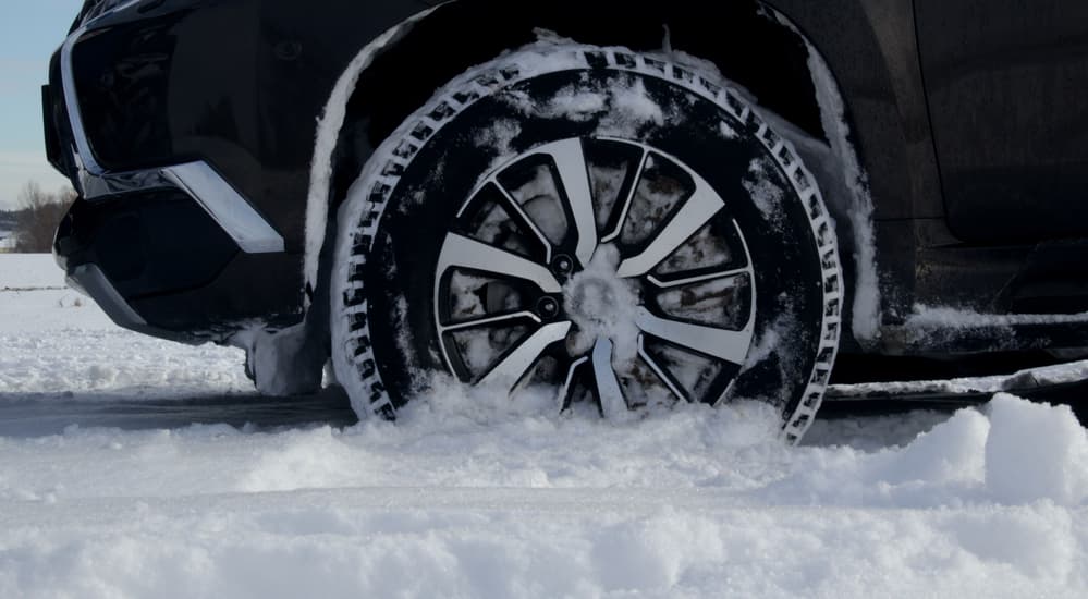 Close up of a winter tire on a snowy ground.